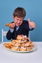 Pies in the hands of a happy boy at lunch at a school desk, copy space Royalty Free Stock Photo