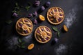 pies with purple plum baked in thin tartlet shells on dark background
