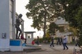 Man photographing woman in front of stone statue.