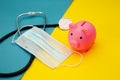 Pig moneybox, face mask and stethoscope on colorful background. Spending money on pills and expensiveness of medicine Royalty Free Stock Photo