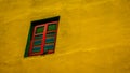 Pigeon perched in front of colorful window amidst a big bright yellow wall Royalty Free Stock Photo