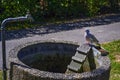 A pigeon that sits on the edge of a stone well and rests