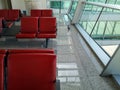 A pigeon walks across the floor past rows of red chairs in a room with large panoramic windows. Bird in empty waiting room of Royalty Free Stock Photo