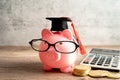 Pigging bank wearing eyeglass with coins and graduation hat; saving bank education concept