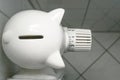 Piggy bank from above on the thermostat of an old radiator, concept for increasing costs of heat and energy, funny perspective,