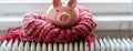 a piggy bank adorned with a winter hat and scarf, positioned next to a warm radiator in a cozy home interior, leaving