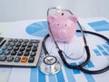 Piggy bank on bar charts and calculator.  stethoscope. Financial analysis concept Royalty Free Stock Photo