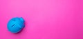 Piggy bank blue color against bright pink background Royalty Free Stock Photo