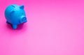 Piggy bank blue color against bright pink background Royalty Free Stock Photo