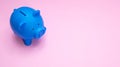 Piggy bank blue color against pastel pink background Royalty Free Stock Photo