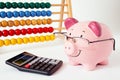 Piggy bank with calculator and abacus on white background.