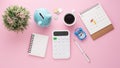 Piggy bank, calculator, calendar, clock and coffee cup on pink desk