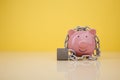 Piggy bank with chain on yellow background. Money security concept Royalty Free Stock Photo