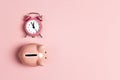 Piggy bank and classic alarm clock on pink background. Time to saving, money, banking concept Royalty Free Stock Photo