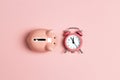 Piggy bank and classic alarm clock on pink background. Time to saving, money, banking concept. Royalty Free Stock Photo