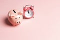 Piggy bank and classic alarm clock on pink background. Time to saving, money, banking concept Royalty Free Stock Photo