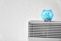 Piggy bank with coins on calorifer at home. Heating saving concept Royalty Free Stock Photo