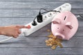 Piggy bank, coins and power strip on table. Electricity saving concept Royalty Free Stock Photo