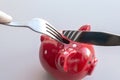 Piggy bank with coins stands on a plate. Cutlery to start eating a dish. Eating savings, consumer savings concept