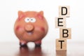 Piggy bank and debt word on wooden blocks