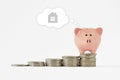 Piggy bank dreaming of buying a home on raising piles of coins - Concept of saving money to buy a home Royalty Free Stock Photo