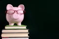 Piggy bank education savings concept, glasses and blackboard copy space Royalty Free Stock Photo