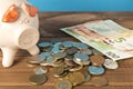 Piggy Bank and a few coins and euro bills on the wooden table. Close up. The concept of saving money. Selective focus Royalty Free Stock Photo