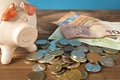 Piggy Bank and a few coins and euro bills on the wooden table. Close up. The concept of saving money. Selective focus Royalty Free Stock Photo