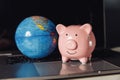 Piggy bank and globe on a laptop. International online banking concept