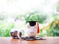 Piggy bank with graduation hat on stack of coins. The concept of saving money for education, student loan, scholarship, tuition Royalty Free Stock Photo