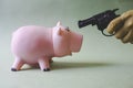 A piggy bank with a gun pointed at it Royalty Free Stock Photo