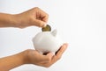 A piggy bank in hand and is putting coins in a piggy bank with copy space on white background