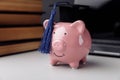 Piggy bank in hat with books close-up. College, graduate, education concept Royalty Free Stock Photo