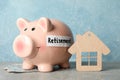 Piggy bank with inscription Retirement, money and wood house against blue background