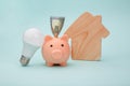 Piggy bank and led light bulb, house figure on blue background. Energy saving concept Royalty Free Stock Photo