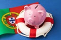 Piggy bank, lifebuoy and flag on a blue background, the concept of saving the Portuguese economy Royalty Free Stock Photo