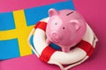 Piggy bank, lifebuoy and flag on a blue background, the concept of saving the Swedish economy Royalty Free Stock Photo