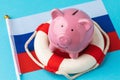 Piggy bank, lifebuoy and flag on a colored background, the concept of saving the Russian economy Royalty Free Stock Photo