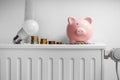 piggy bank, light bulb and coins on radiator Royalty Free Stock Photo