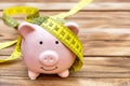Piggy bank with measure tape on wooden background. Copy space Royalty Free Stock Photo