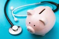 Piggy bank and medical stethoscope on a blue background. Concept on the topic of accumulating money for treatment Royalty Free Stock Photo