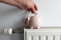 Piggy bank and money on heating radiator with temperature regulator