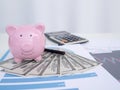 Piggy bank on pile of dollar, graph and calculator.  stethoscope.  Financial analysis concept Royalty Free Stock Photo