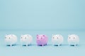 Piggy bank pink colour outstanding among piggy bank white on light blue background Royalty Free Stock Photo