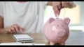 Piggy bank with plug of electric cord and person calculates electricity costs on calculator