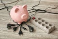 Piggy bank, plugs and power strip on floor. Electricity saving concept