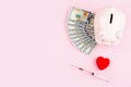 Piggy bank, red heart, cash money and syringe on pink background with copy space, flat lay, top view. Concept for money Royalty Free Stock Photo