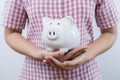 Piggy bank savings. Female holding pink piggy bank on white background