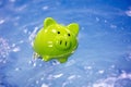 Piggy bank sinking in water drowning in debt