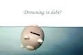 A piggy bank sinks in dark murkey water, representing the idea of drowning in debt, or keeping your head above water and other Royalty Free Stock Photo